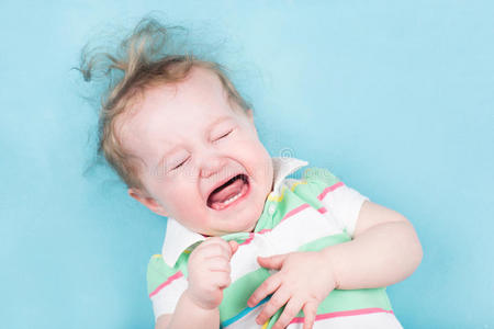 可爱的婴儿在蓝色毯子上哭泣