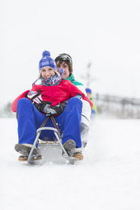一对在雪中享受雪橇旅行的年轻夫妇的全长肖像