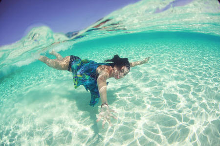 一个穿着连衣裙的女子在海洋潜水中游泳