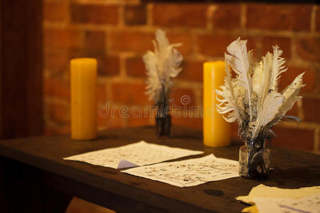 羽毛笔在木制桌子上画蜡烛和旧纸。酿造的。