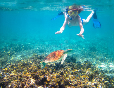 在热带海洋中，孩子们在海龟旁边浮潜