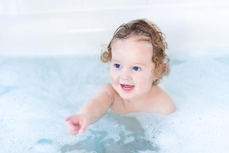 可爱的微笑女婴在浴缸里玩泡沫