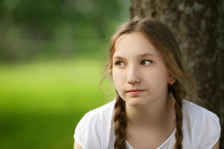 女孩坐在公园里的树旁