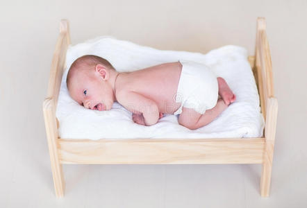 可爱的新生婴儿躺在木制玩具床上