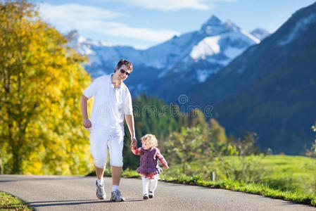 父亲带着孩子在雪山之间的路上