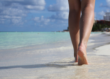 在与脚印的热带沙滩上的的腿。步行的女性