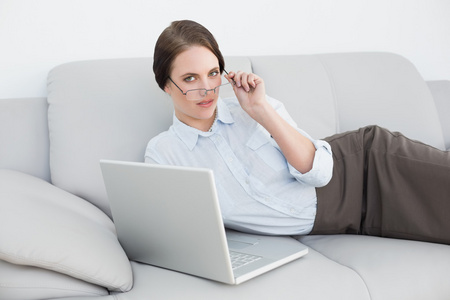 一个穿得潇洒漂亮的女人，在沙发上使用笔记本电脑的肖像