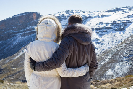 夫妇在毛皮帽夹克看大雪山脉图片