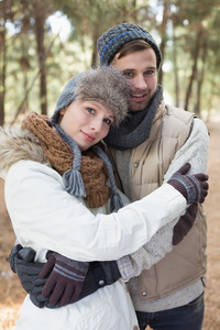 夫妇在冬季服装拥抱在树林里