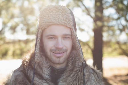 在暖和的衣服，在森林里的男人微笑着的特写肖像