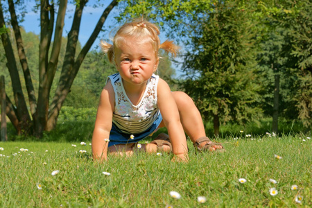 孩子，在草地上，他的脸上做了个鬼脸玩的小女孩
