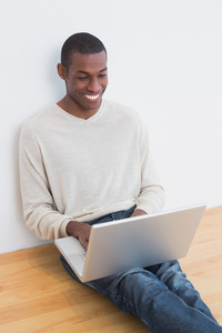 快乐休闲黑人年轻人在地板上使用便携式计算机