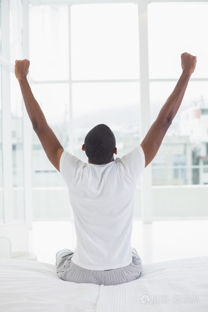 黑人男子躺在床上醒来伸伸胳膊