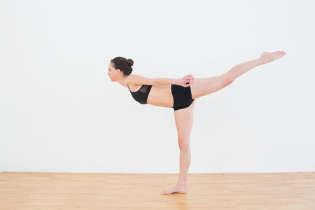 运动型的年轻女人站在一条腿在健身中心