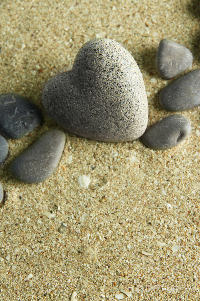 灰色的石头在心,砂背景上的形状