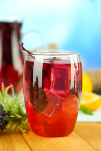 红罗勒柠檬水在水罐和玻璃 木桌上，在明亮的背景上