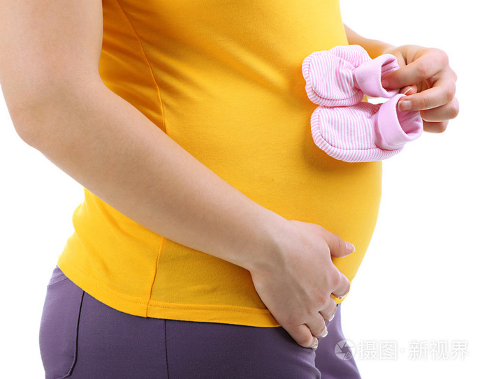 怀孕的妇女抱着粉红色婴儿鞋上白色孤立