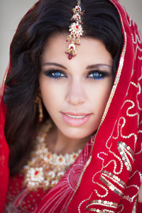 美丽的印度女人的传统红色裙子和黄金首饰户外