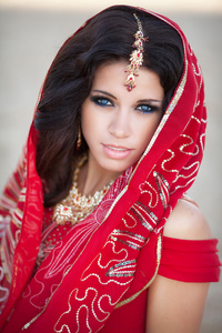 美丽的印度女人的传统红色裙子和黄金首饰户外