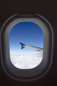 飞机窗口与翼和多云的天空在后面