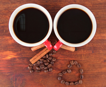 红杯子的浓咖啡和咖啡豆木制背景上