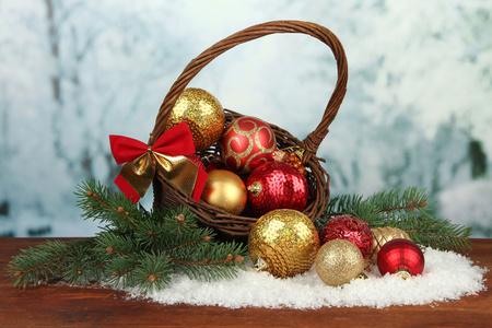 在篮子里在明亮的背景上的表有雪的圣诞装饰品