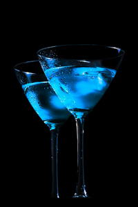 鲜蓝色与黑色背景上的冰鸡尾酒的眼镜