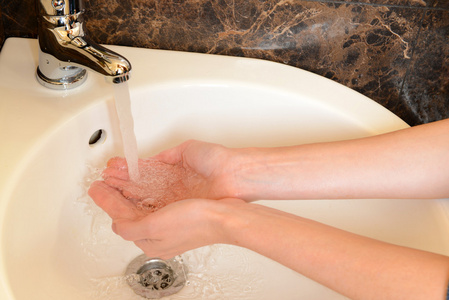 人类正在浴室水龙头下洗过的手的特写