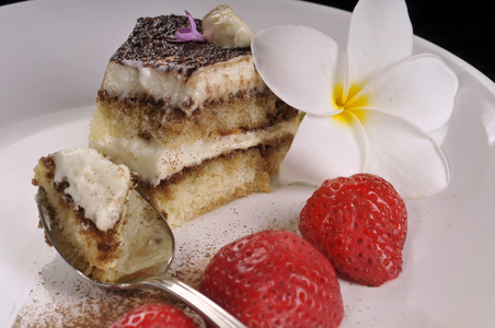 提拉米苏蛋糕配含着银汤匙新鲜草莓