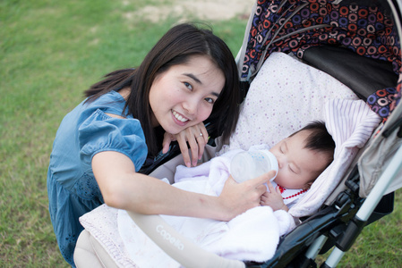 快乐亚洲母亲给婴儿车上的婴儿喂食