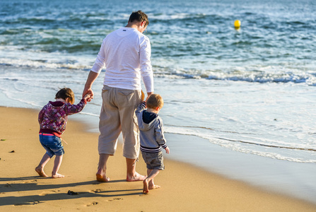 两个孩子和他们的爸爸玩站在海洋