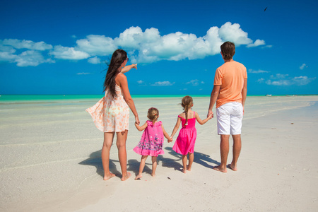 背视图的四人家庭在加勒比海滩度假