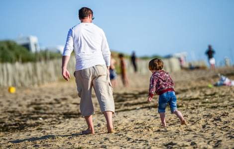 爸爸走在沙滩上用他年轻的孩子