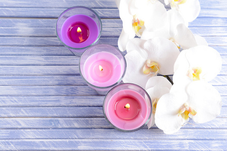 美丽五颜六色的蜡烛和兰花鲜花的色彩木制背景