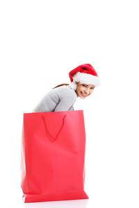 美丽的女孩穿着红色购物袋的圣诞老人的帽子