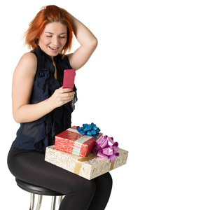 幸福的红发女人与一个礼品盒和一个白色背景上的电话