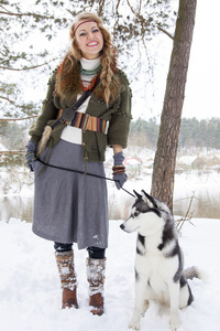 快乐的年轻女人站在西伯利亚爱斯基摩狗