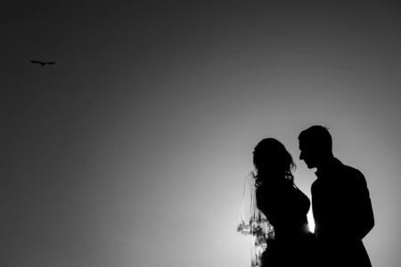 年轻的新娘和新郎在日落背景上的剪影