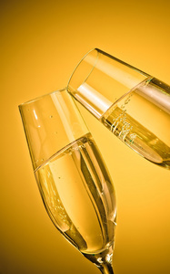 两个香槟笛子与金色的泡泡，在金黄的光线背景