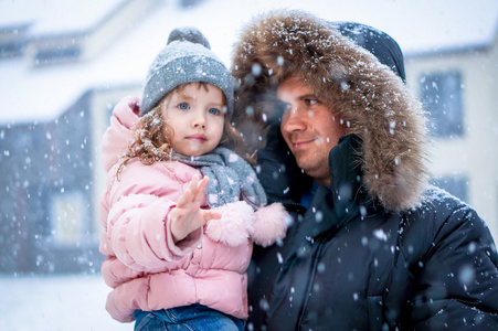 父亲和女儿 enhoying 雪吹在白天