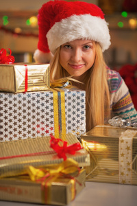 在圣诞老人的帽子与堆叠的本盒上圣诞快乐十几岁的女孩