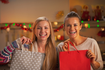 在圣诞节装饰微笑着购物袋的两个女友