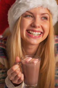 微笑着十几岁的女孩，在圣诞老人的帽子与杯热巧克力的肖像