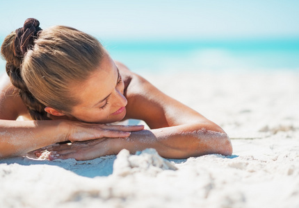 幸福的年轻女人放松而躺在沙地 bea 的泳衣