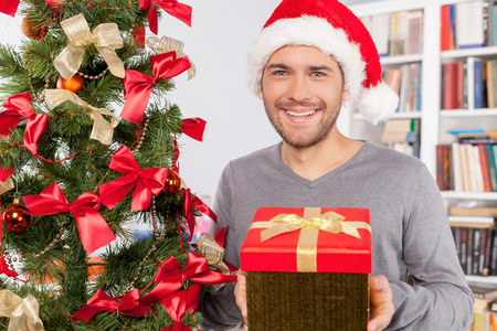 男人抱着附近圣诞树上的礼品盒