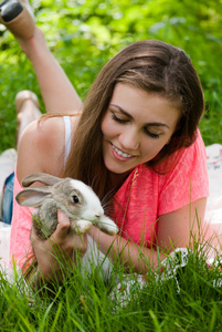 年轻快乐的女人拥抱户外的小兔子