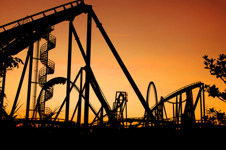 会场游戏在日落时分的嘉年华期间的过山车的剪影照片