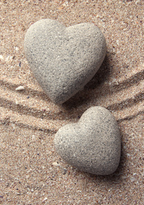 灰色的禅宗石在心，砂背景上的形状