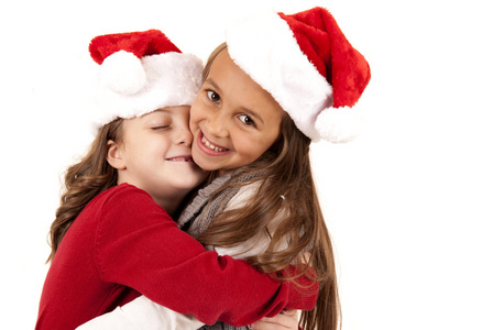 两个年轻女孩戴着圣诞帽拥抱