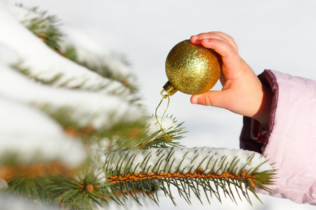 孩子挂在圣诞树上球在冬天